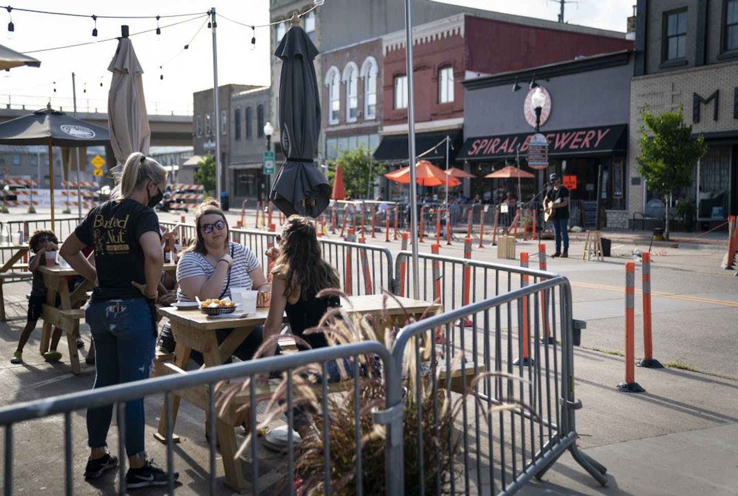 Renee Pachan and Taylor Sullivan gave their order to a server as they met for dinner at the outdoor patio at the Busted Nut Bar and Grill on a blocked off street in downtown Hastings, Minn., on Friday, July 24, 2020. At right across the street was a musical, Matt Browne, who was hired by Spiral Brewery to play music on the street.