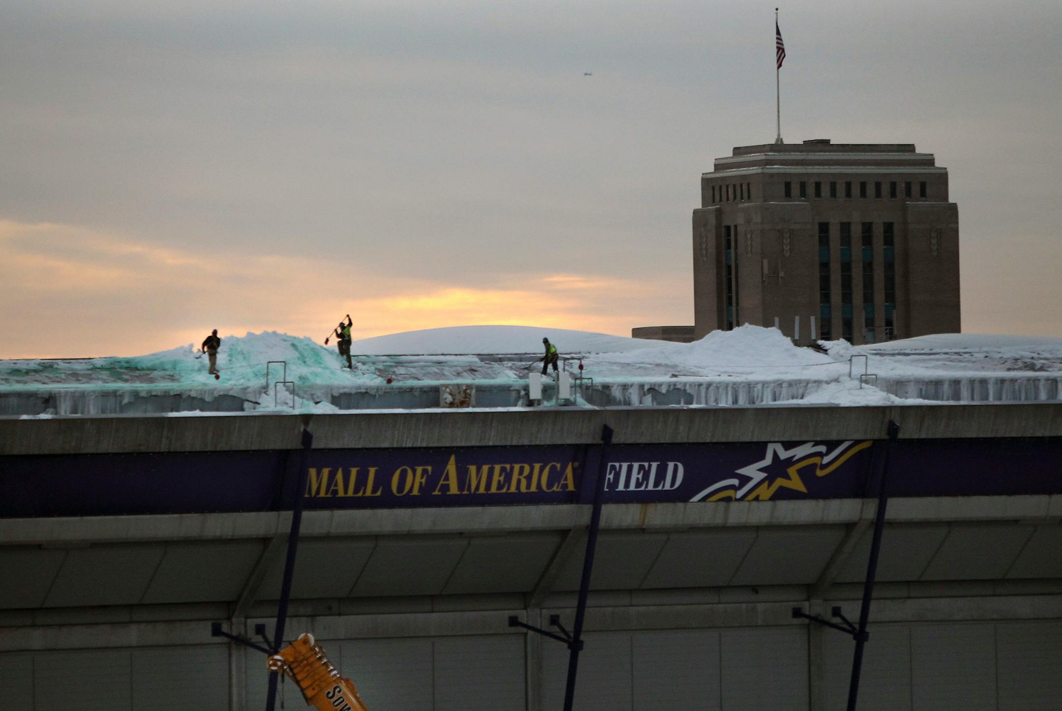 Crews work on shoveling snow from the dome early Tuesday morning.