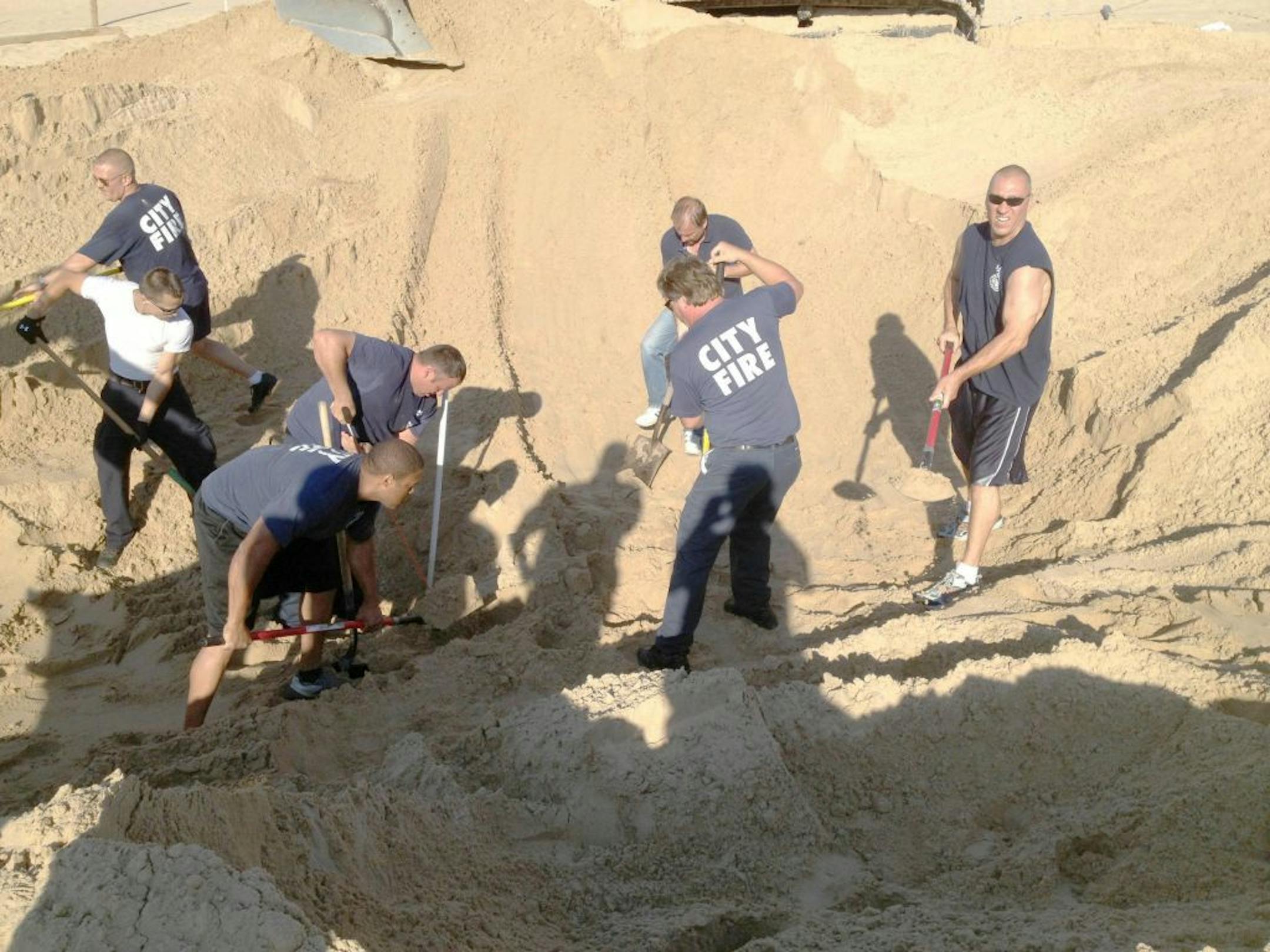 Michigan City police and firefighters dig with shovels to rescue 6 year old Nathan Woessner, of Sterling, Ill., who was trapped for over three hours under about 11 feet of sand at Mount Baldy dune near Michigan City, Ind., on Friday July 12, 2013.