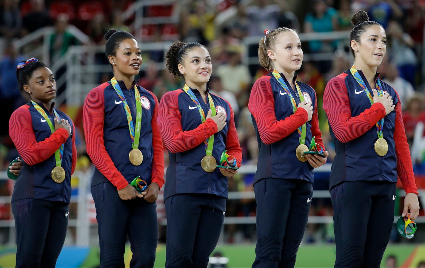 U.S. gymnasts and gold medallists, left to right, Simone Biles, Gabrielle Douglas, Lauren Hernandez, Madison Kocian and Aly Raisman stand for their national anthem during the medal ceremony for the artistic gymnastics women's team at the 2016 Summer Olympics in Rio de Janeiro, Brazil, Tuesday, Aug. 9, 2016.