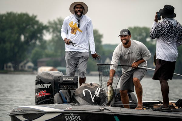 Randy Moss reacted after catching a large mouth bass during the tournament as Dane Vocelka (netting the fish) guided Moss and his friend Lee Vickers.