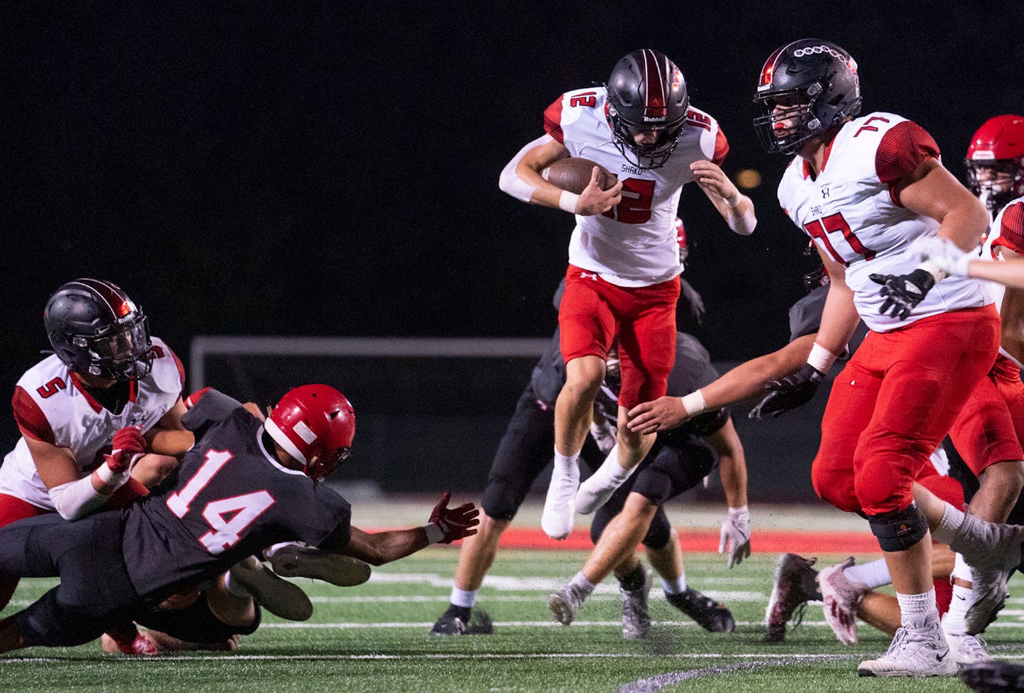 Shakopee quarterback Leyton Kerns (12) leaped over Eden Prairie defenders as he scrambled in the first half. ]