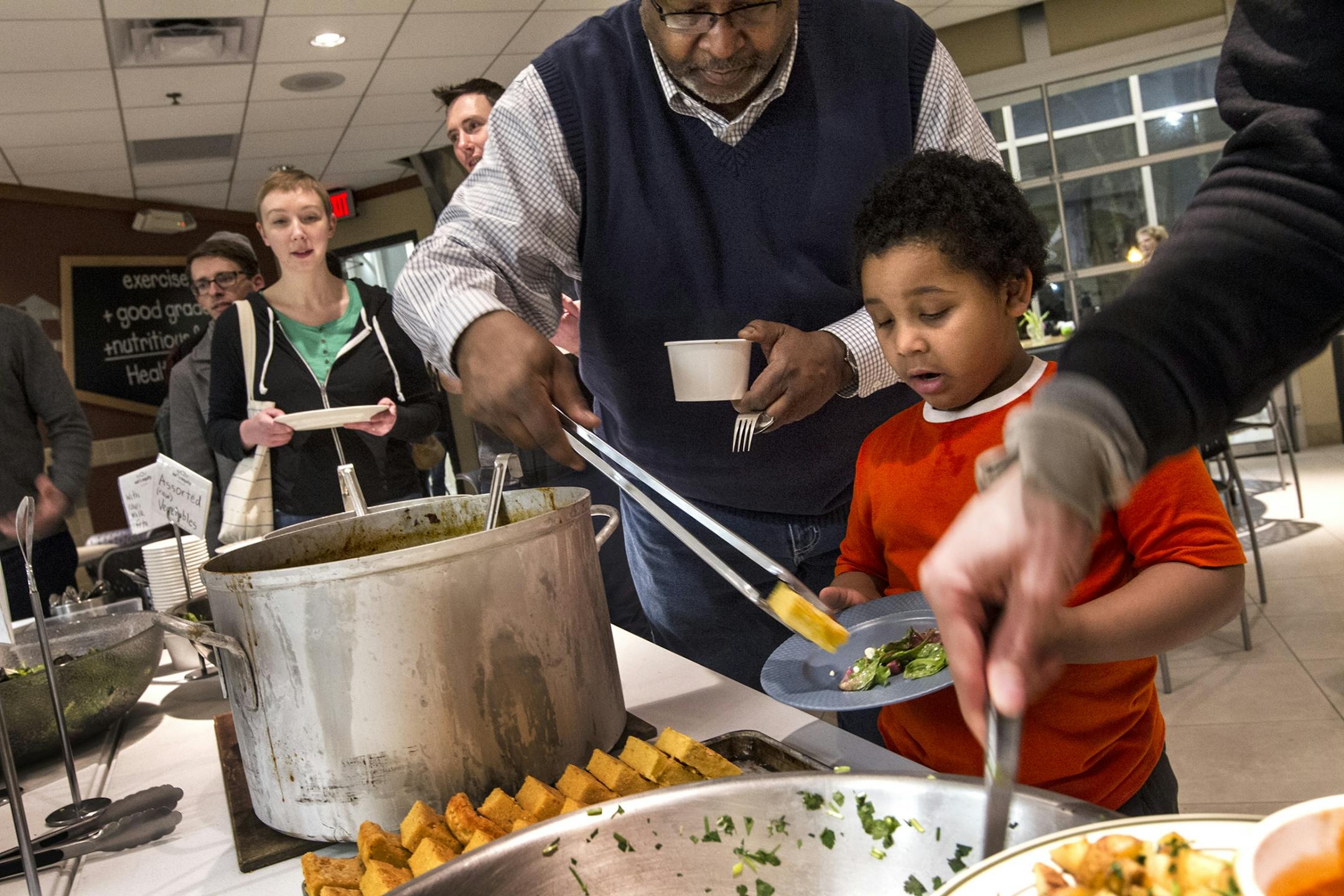 Urban Ventures Ready Set Work director Stan Hill loads a plate for his grandson Ishaan Crawford, 5, at Eat for Equity's community feast benefitting Urban Ventures at the Urban Ventures headquarters in Minneapolis January 31, 2015.