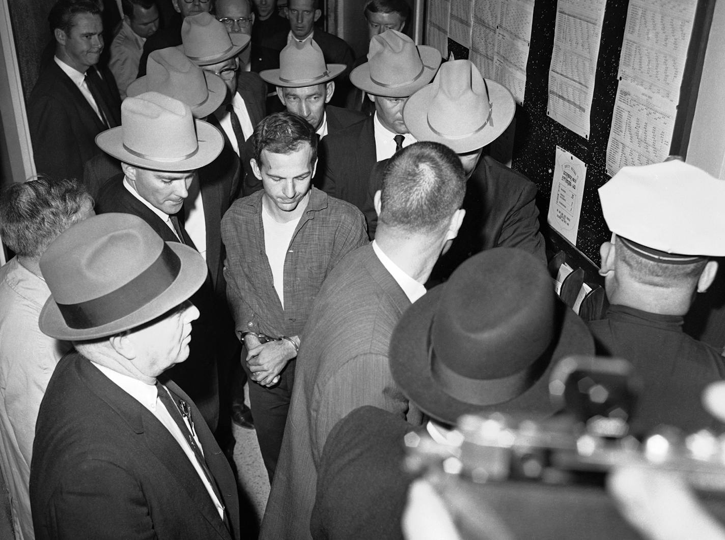 Lee Harvey Oswald, center, is shown in custody at a Dallas police station, Nov. 23, 1963. Oswald is accused in the assassination of President John F. Kennedy. Others are unidentified. (AP Photo)