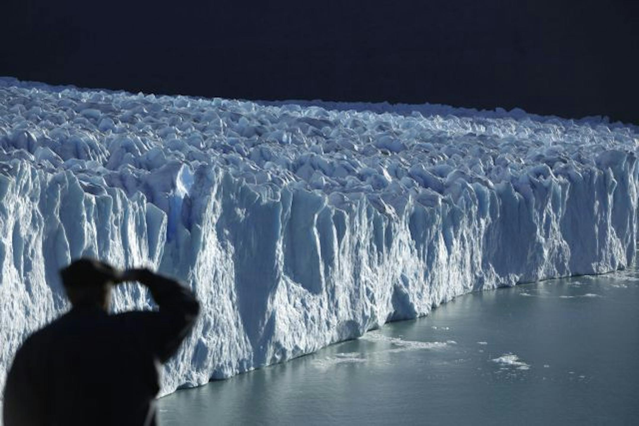A tourist looks out at the Perito Moreno Glacier as it descends into Argentino Lake in Los Glaciares National Park in Santa Cruz province in the Patagonia region of southern Argentina, Monday, April 20, 2009.