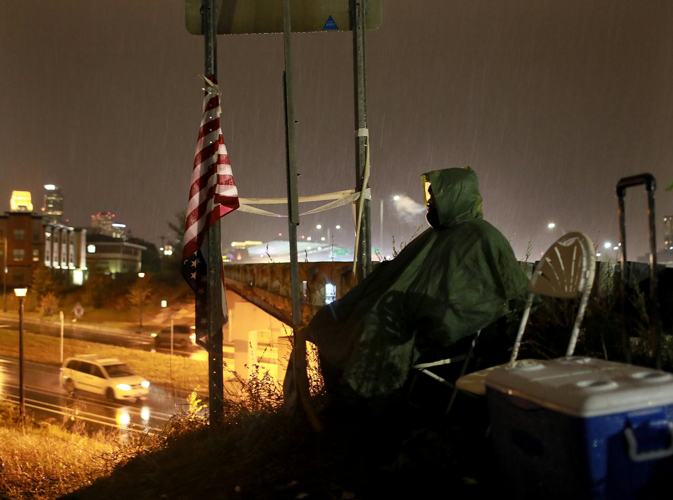 Baba Dook, 40, who recently moved to Minneapolis with his wife from California and a member of Natives Against Heroin, keeps an eye on the camp while working security for NAH in the cold rain Thursday, Oct. 4, 2018, in Minneapolis, MN.