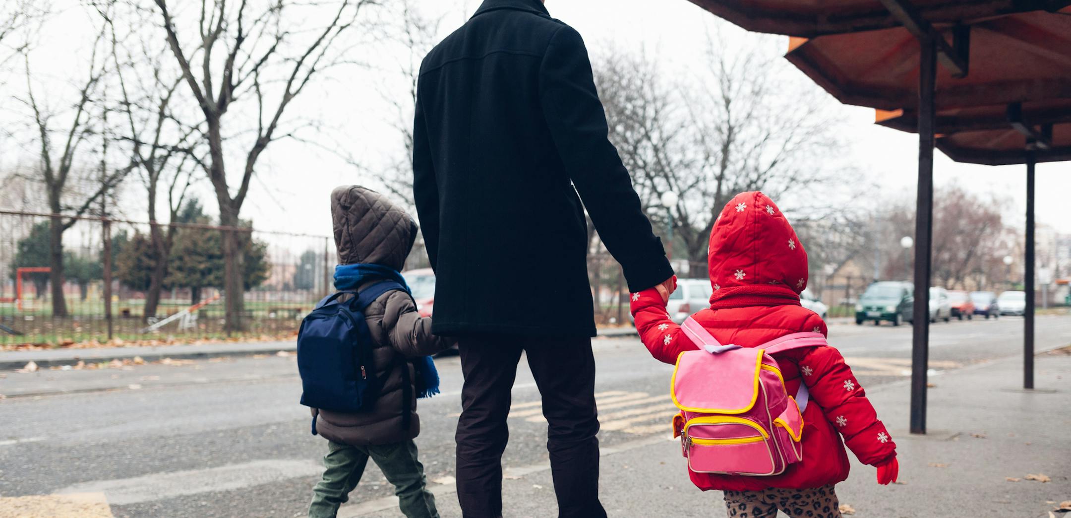 iStock
Dad with kids going to the bus stop.