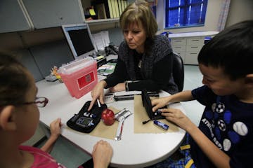 School nurse Bernadette Bien assisted with 4th grade students Alex Higgins and Megan Rittinger (pink shirt) with their insulin pump at Hidden Valley E