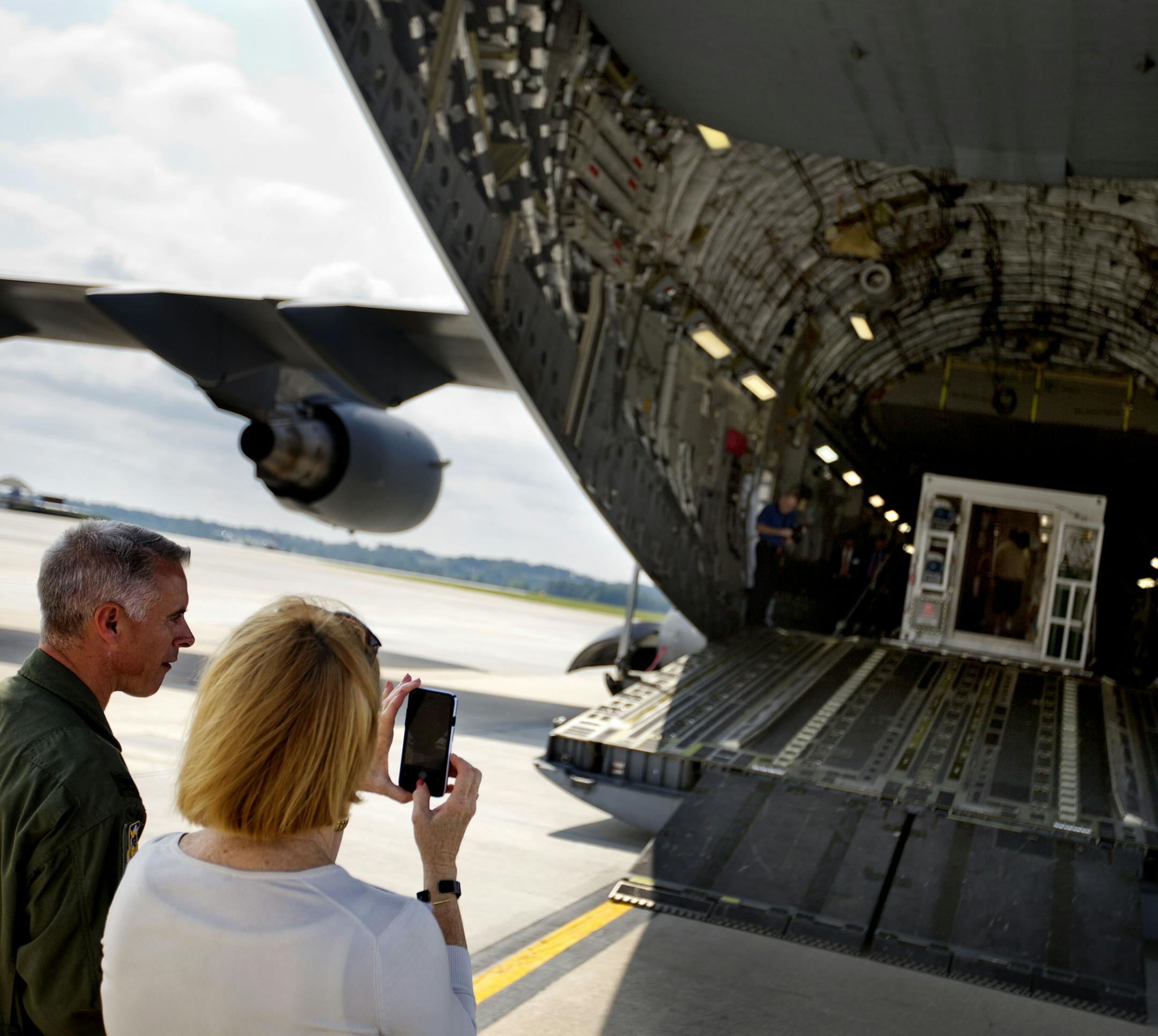 CORRECTS TO C-17 FROM B-17 - Guests on a tour take a photo of a medevac biocontainment unit displayed aboard a C-17 military transport plane at Dobbins Air Force Reserve Base, Tuesday, Aug. 11, 2015, in Marietta, Ga. The State Department and partners unveiled the new public-private containerized biocontainment system for highly contagious pathogens Tuesday. The first of their kind units, owned and operated by the U.S. State Department and housed at Dobbins, can roll on and off planes to help eva