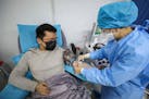 This photo taken on February 18, 2020 shows a doctor, left, who has recovered from the COVID-19 coronavirus infection donating plasma in Wuhan, China.