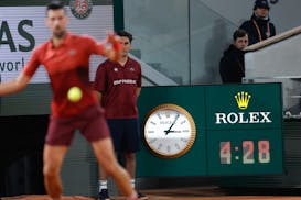 Serbia's Novak Djokovic plays a shot against Italy's Lorenzo Musetti as the clock indicates the match time played in the fifth set of their third roun