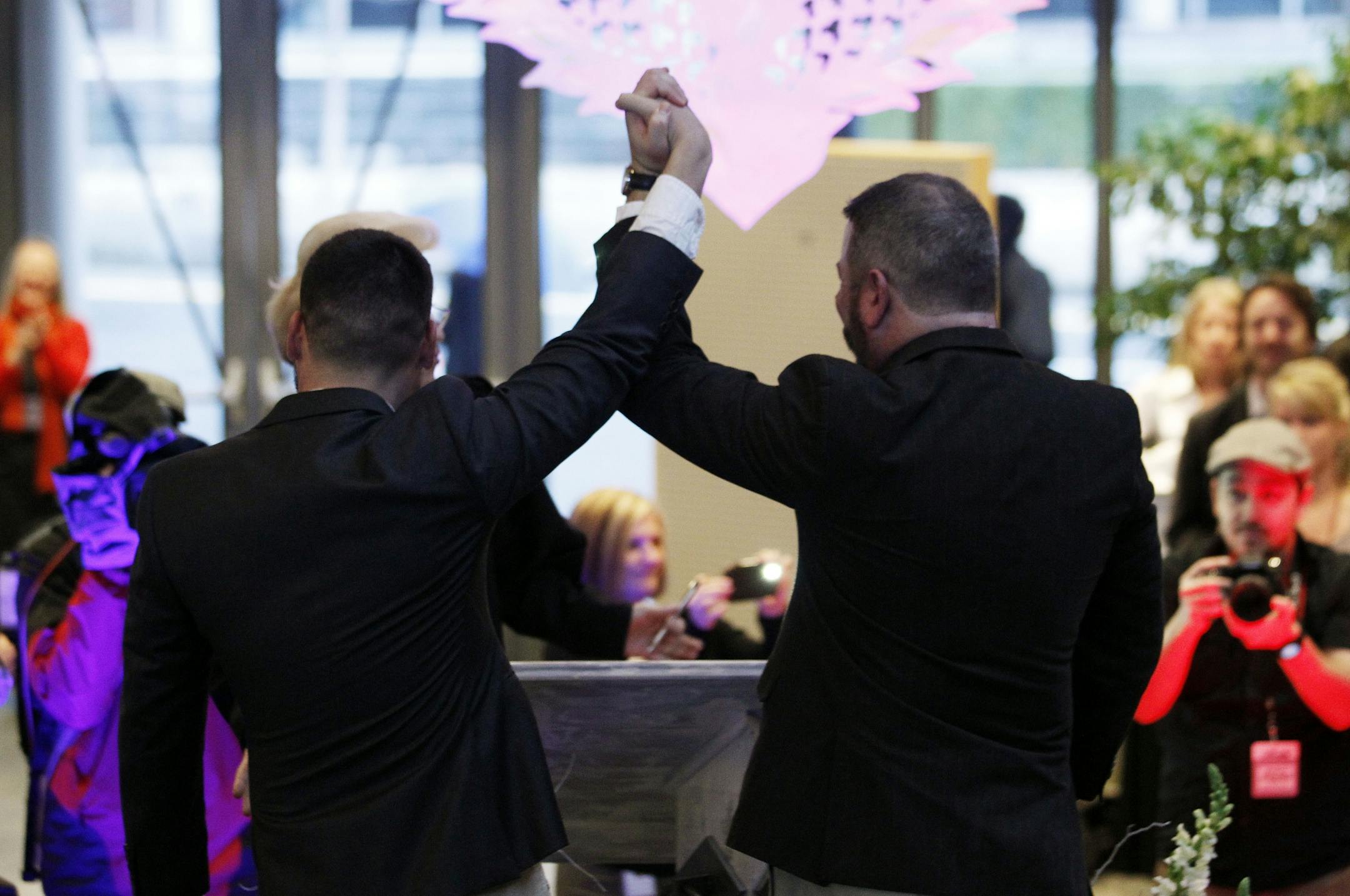 Newlyweds Corianton Hale, left, and Keith Bacon raise their arms in celebration after marrying at Seattle City Hall, Sunday, Dec. 9, 2012, in Seattle.