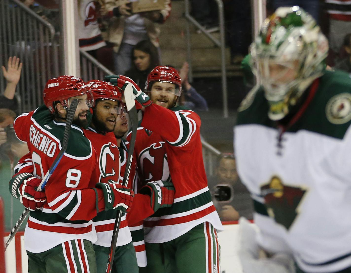 New Jersey Devils players celebrate a goal by Devante Smith-Pelly, second from left, against Minnesota Wild goalie Darcy Kuemper, right, during the second period of an NHL hockey game, Thursday, March 17, 2016, in Newark, N.J. (AP Photo/Julio Cortez)