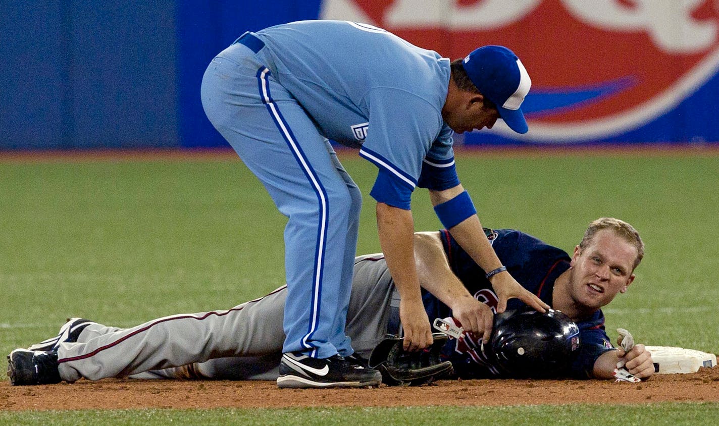 Toronto Blue Jays' John McDonald,left, checks on Minnesota Twins Justin Morneau after the pair collided at second base after Twins' Michael Cuddyear grounded into fielders choice during eighth inning baseball action in Toronto Wednesday, July 7, 2010. (AP Photo/The Canadian Press,Chris Young)