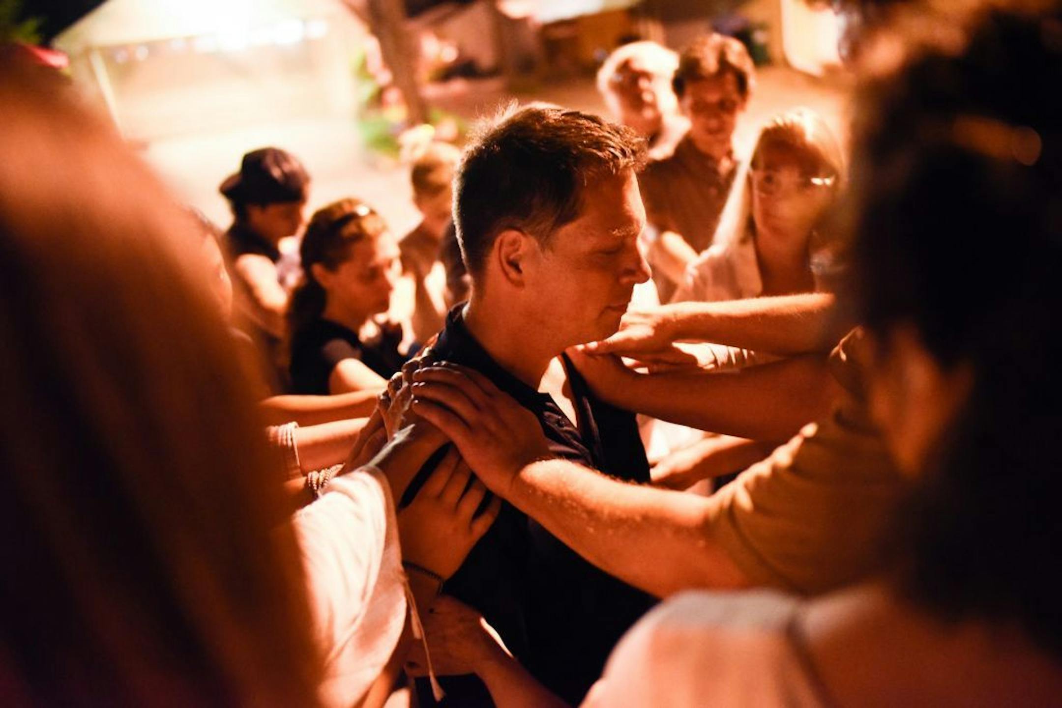 Friends and neighbors of Don Damond placed their hands on him during a prayer Saturday night at a candlelight vigil memorializing the one year anniversary of Justine Damond Ruszczyk's death.