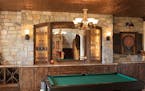 An arched stone wall, knotty alder cabinets, tin ceiling and iron sconces add Old World flavor to the new kid and adult hangout.