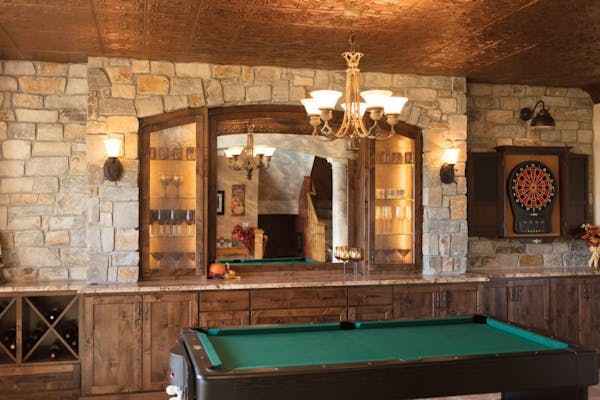 An arched stone wall, knotty alder cabinets, tin ceiling and iron sconces add Old World flavor to the new kid and adult hangout.