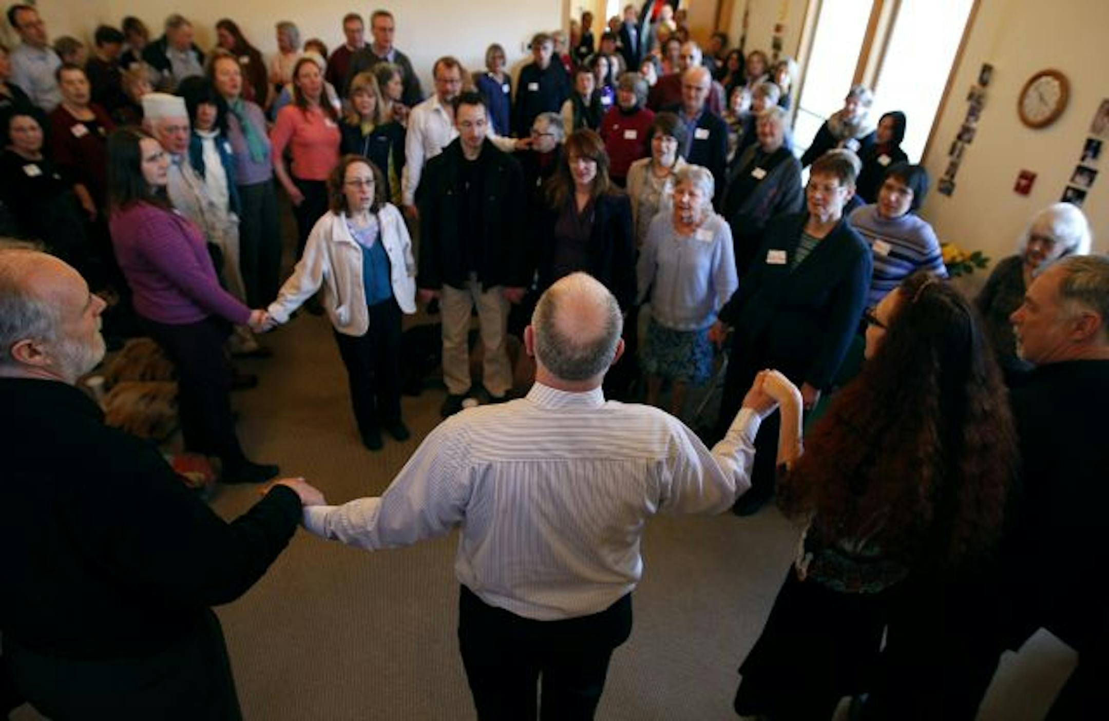 People gathered and held hands as they sang with Howard Bell (middle-in stripped shirt) at a celebration honoring his retirement at Pathways in Minneapolis on Sunday.