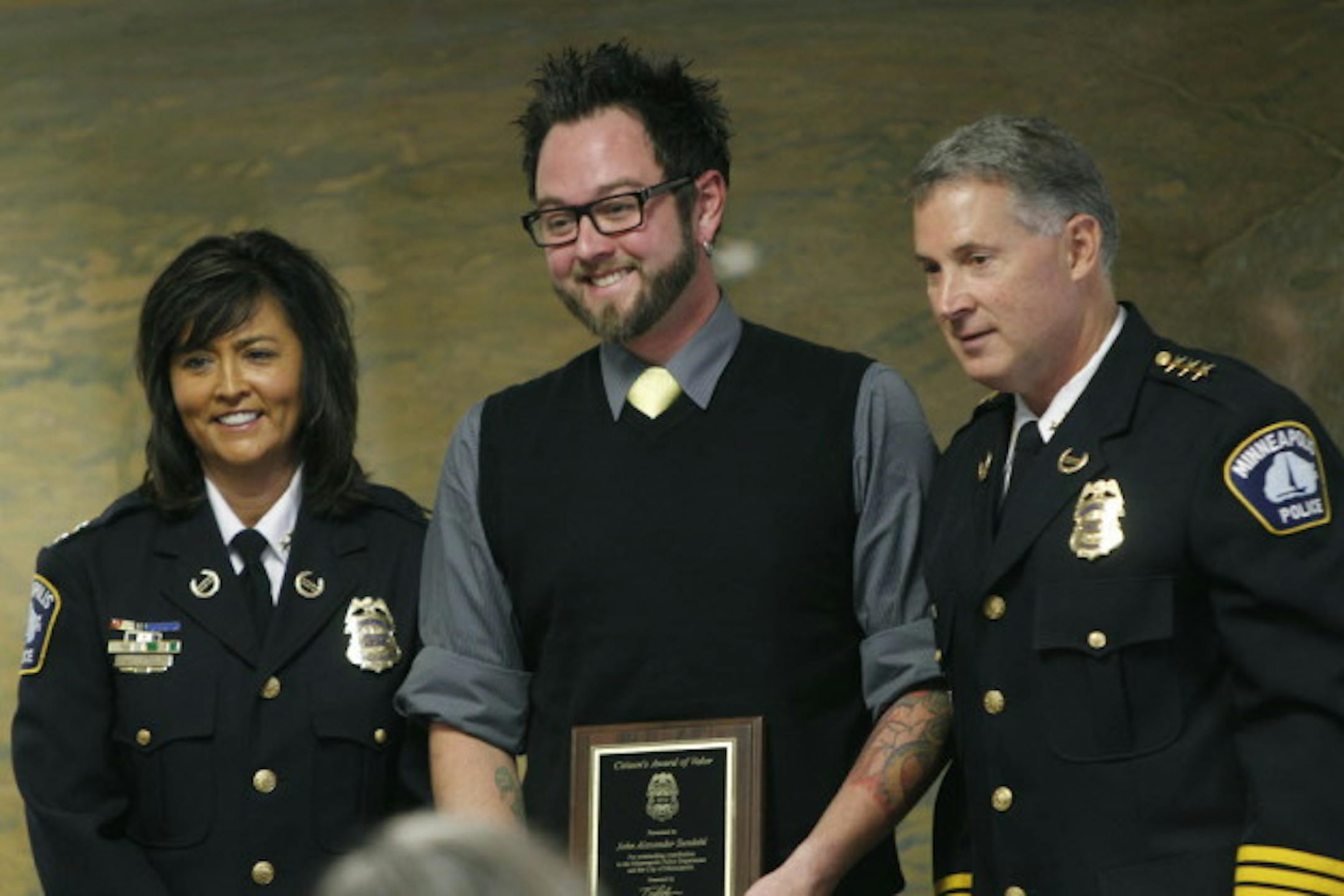 John Sundahl (center) receives an award from outgoing Chief Tim Dolan (right) and his likely successor, Assistant Chief Janée Harteau.