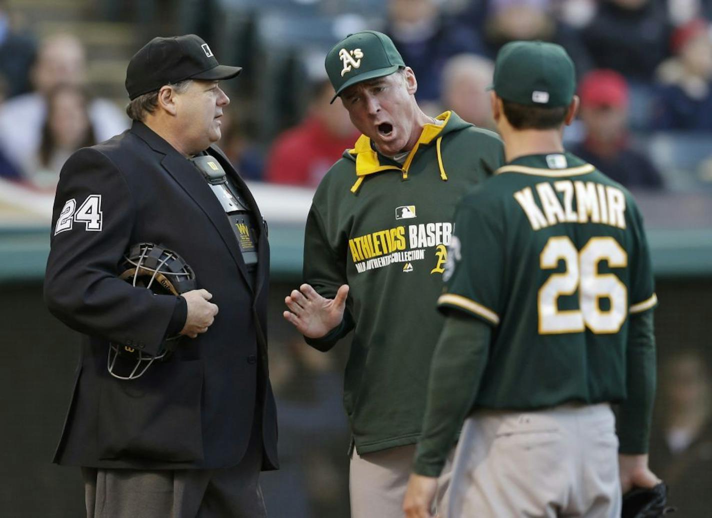 Oakland Athletics manager Bob Melvin, center, argues with home plate umpire Jerry Layne as starting pitcher Scott Kazmir listens during the second inning of a baseball game against the Cleveland Indians, Saturday, May 17, 2014, in Cleveland. Kazmir was ejected from the game.