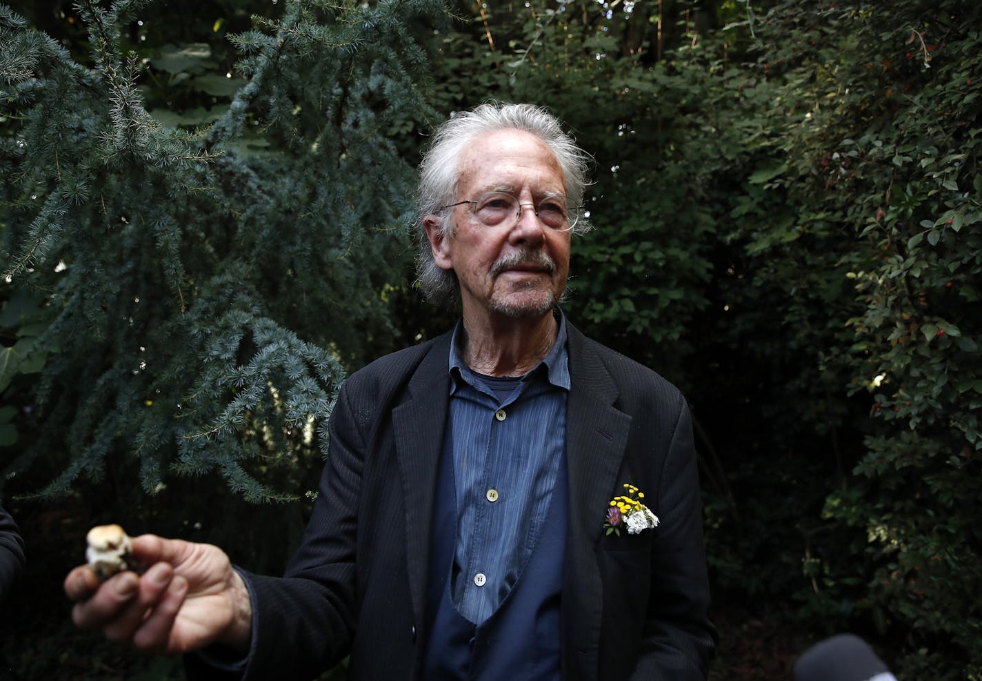 Austrian author Peter Handke holds a mushroom that he picked during a walk near his house as he poses for a photo in Chaville near Paris, Thursday, Oct. 10, 2019. Handke was awarded the 2019 Nobel Prize in literature earlier Thursday. (AP Photo/Francois Mori)