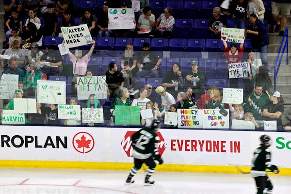 Boston players warm up in front of fans holding signs before the start of Game 5 of the PWHL Walter Cup finals against Minnesota on Wednesday in Lowel