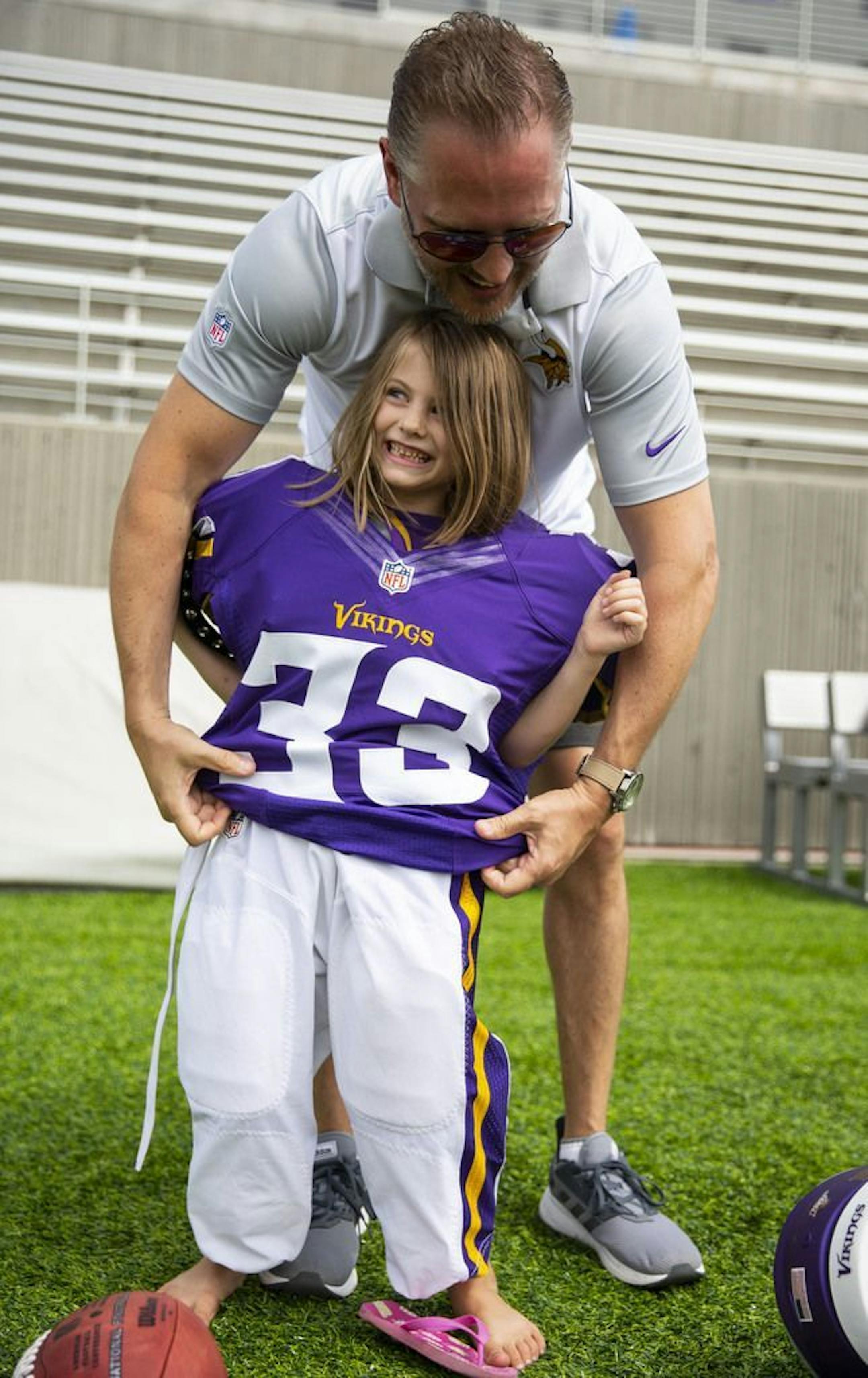 (From left) Elliana Kojoen is helped into a pair of large padded football pants by her dad, Mike, at one of the "Kids Combine" stations in the Kid's Zone at Vikings training camp. ALEX KORMANN • alex.kormann@startribune.com The Minnesota Vikings opened up their first full day of training camp on Friday July 26, 2019 at TCO Performance Center in Eagan, MN. Doors opened to fans at 11AM to watch their favorite players practice and get excited for the 2019 NFL season.