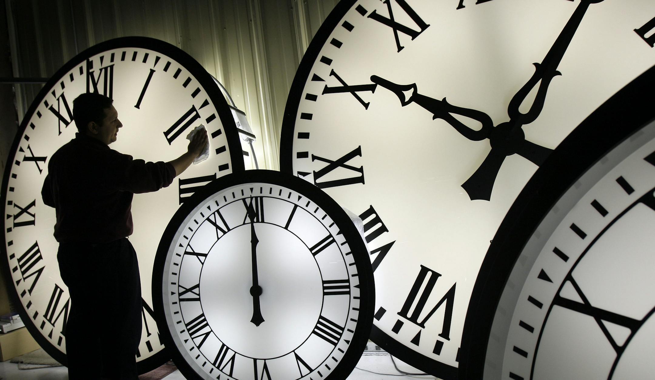 Electric Time Co. employee Walter Rodriguez cleans the face of an 84-inch Wegman clock at the plant in Medfield, Mass. Thursday, Oct. 30, 2008. Daylight savings time ends early Sunday morning with clocks turned back one hour. (AP Photo/Elise Amendola) ORG XMIT: MIN2013030815590138