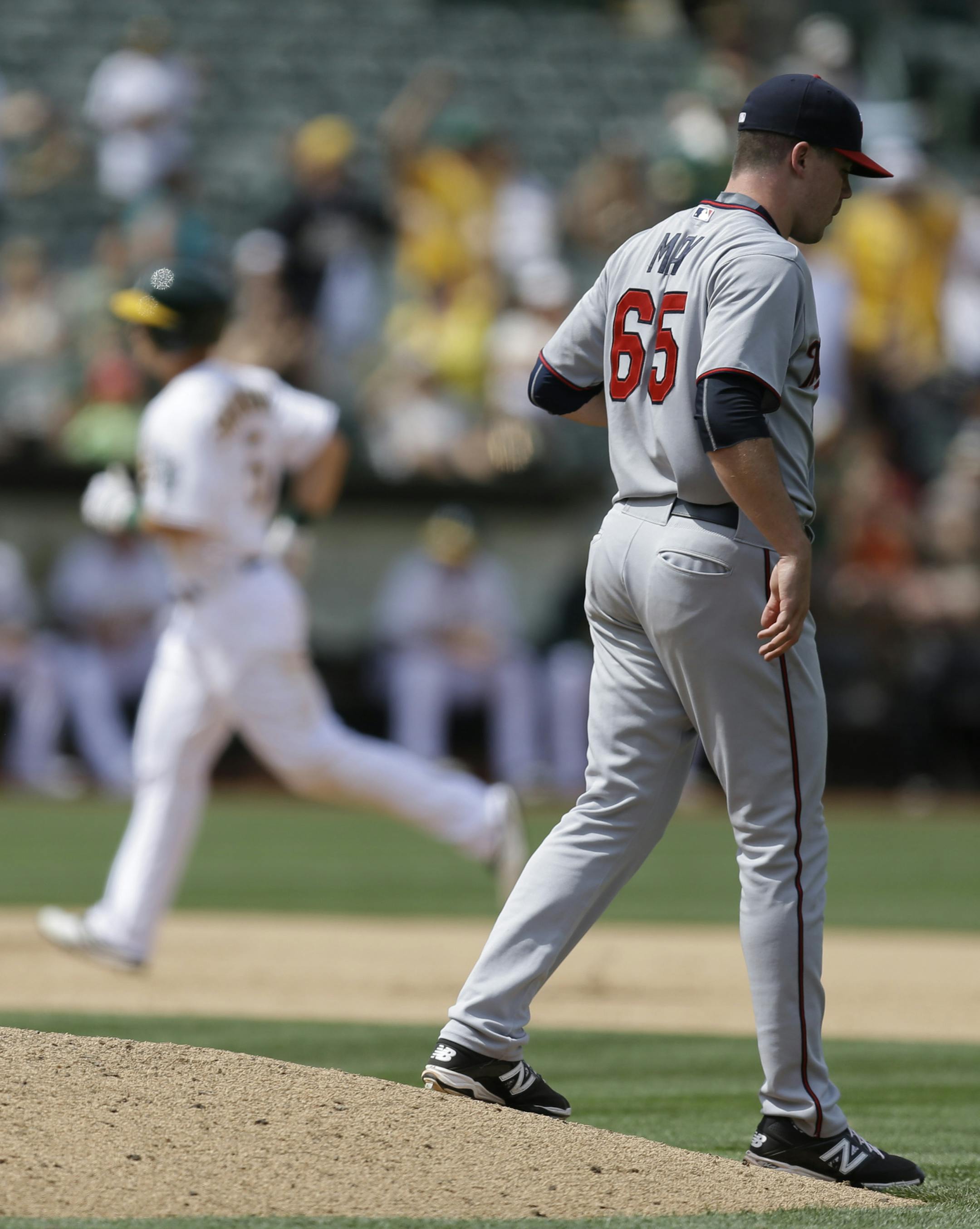 Minnesota Twins' Trevor May, right, walks off the mound after giving up a three run home run to Oakland Athletics' Jake Smolinski, running the bases, in the eighth inning of a baseball game Sunday, July 19, 2015, in Oakland, Calif. (AP Photo/Ben Margot)