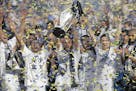 FILE - In this Dec. 7, 2014 file photo, Los Angeles Galaxy's Landon Donovan, center, hoists the trophy as he and teammates celebrate after winning the