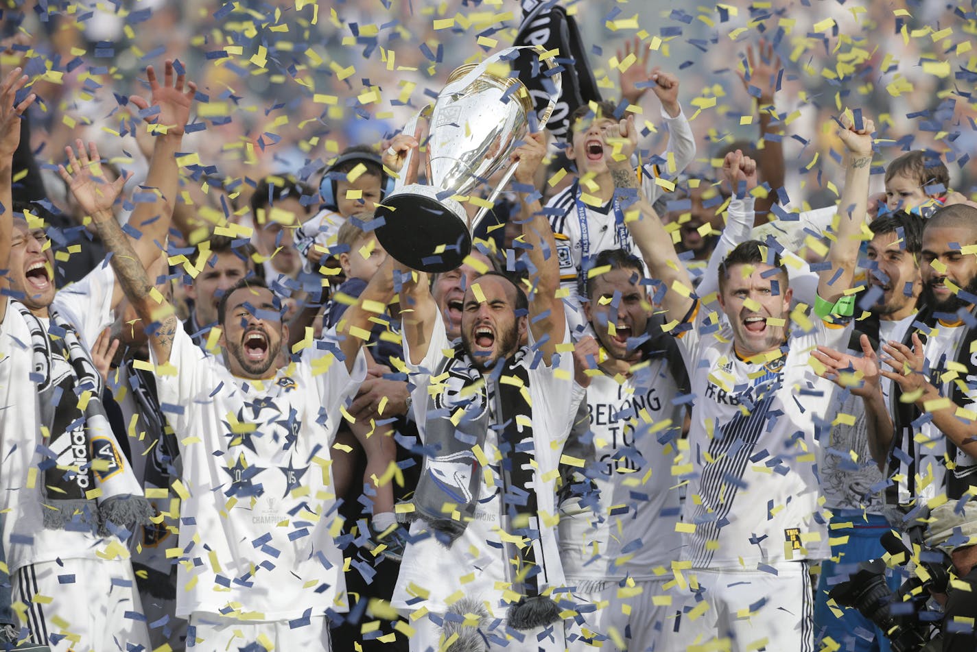 FILE - In this Dec. 7, 2014 file photo, Los Angeles Galaxy's Landon Donovan, center, hoists the trophy as he and teammates celebrate after winning the MLS Cup championship soccer match against the New England Revolution in Carson, Calif. The photo was part of a series of images by photographer Jae C. Hong which won the Thomas V. diLustro best portfolio award for 2014 given out by the Associated Press Sports Editors during their annual winter meeting in Orlando, Fla. (AP Photo/Jae C. Hong, File)