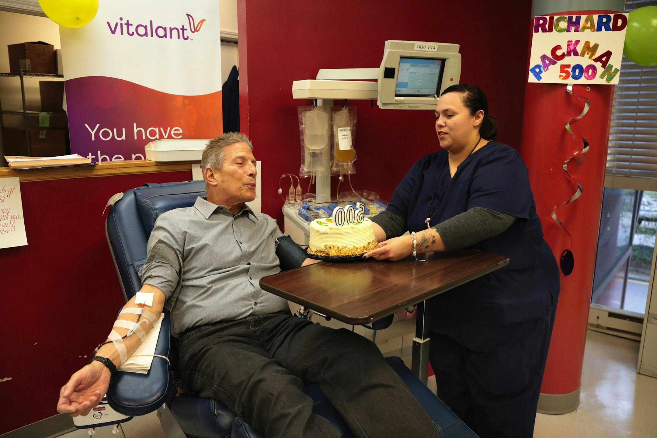 Donor care specialist Nora Martinez held out a cake with candles as Richard Packman, 74, blew them out while donating platelets at Vitalant in Chicago's Thompson Center This was the 500th time Packman donated blood or platelets.