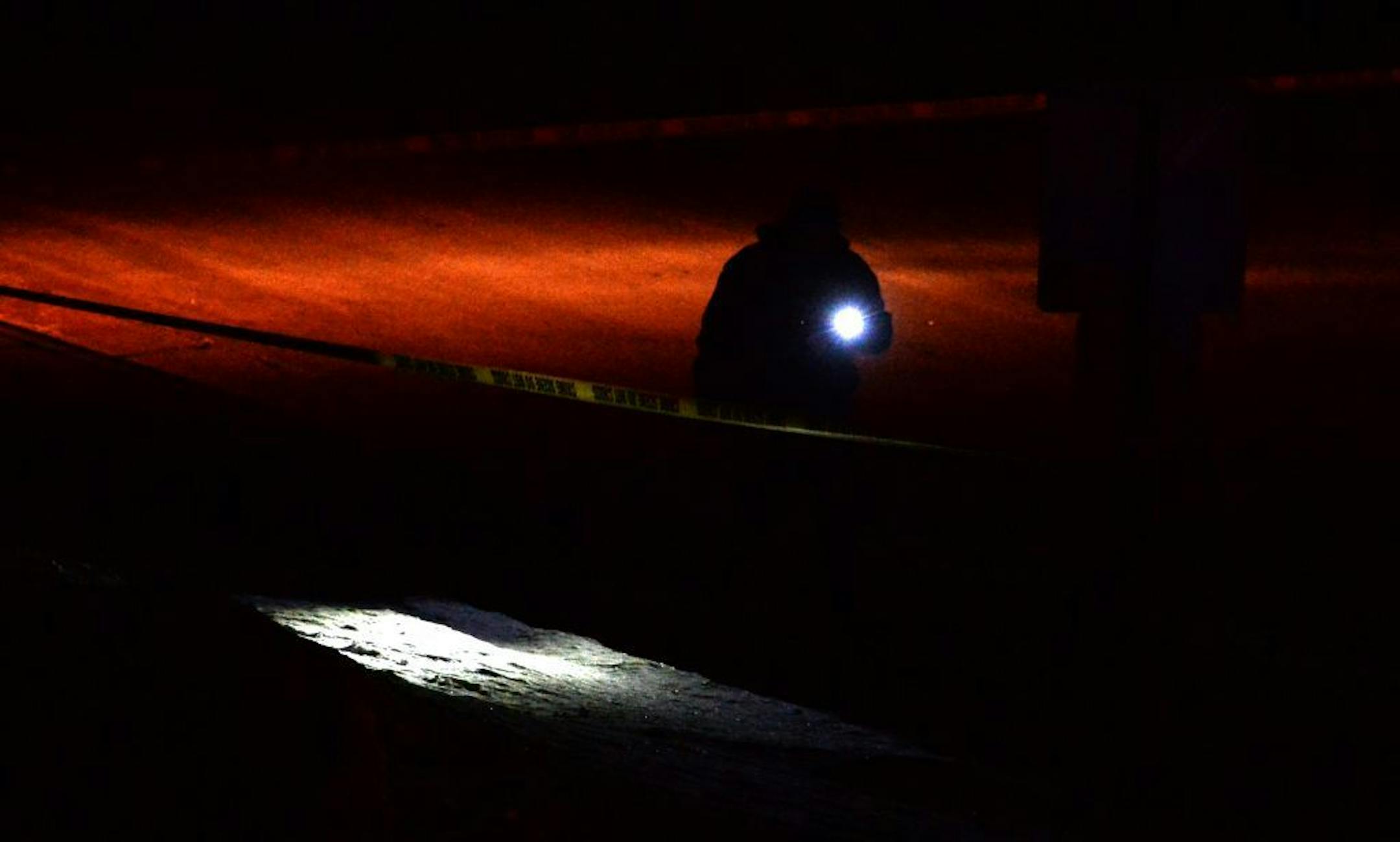 An investigator scanned along the side of Rockford Road near Northwest Blvd. with his flashlight while looking for evidence late Friday night.