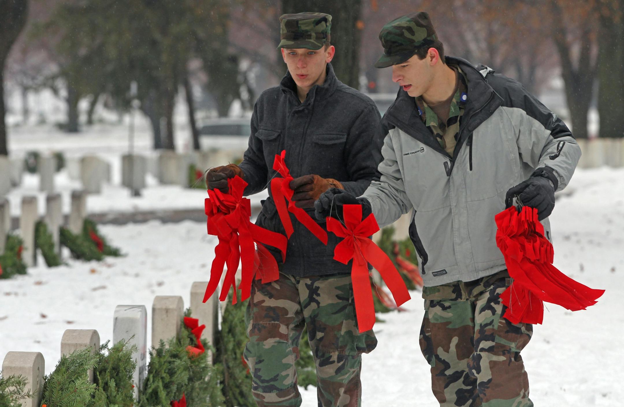 (left to right) Civil Air Patrol Staff Sgt. Andrew Glerum from Eagan and 2nd Lt. Kemal Durgutovic, from Burnsville placed bows on the wreaths during the Wreaths Across America event at the Fort Snelling National cemetary. Several hundered members of the Civil Air Patrol, Patriot Guard, representatives from the military services, veterans and other volunteers laid thousands of wreaths on the graves at Fort Snelling National Cemetary on 12/15/12. Fort Snelling National Cemetery hosted Wreaths Acro