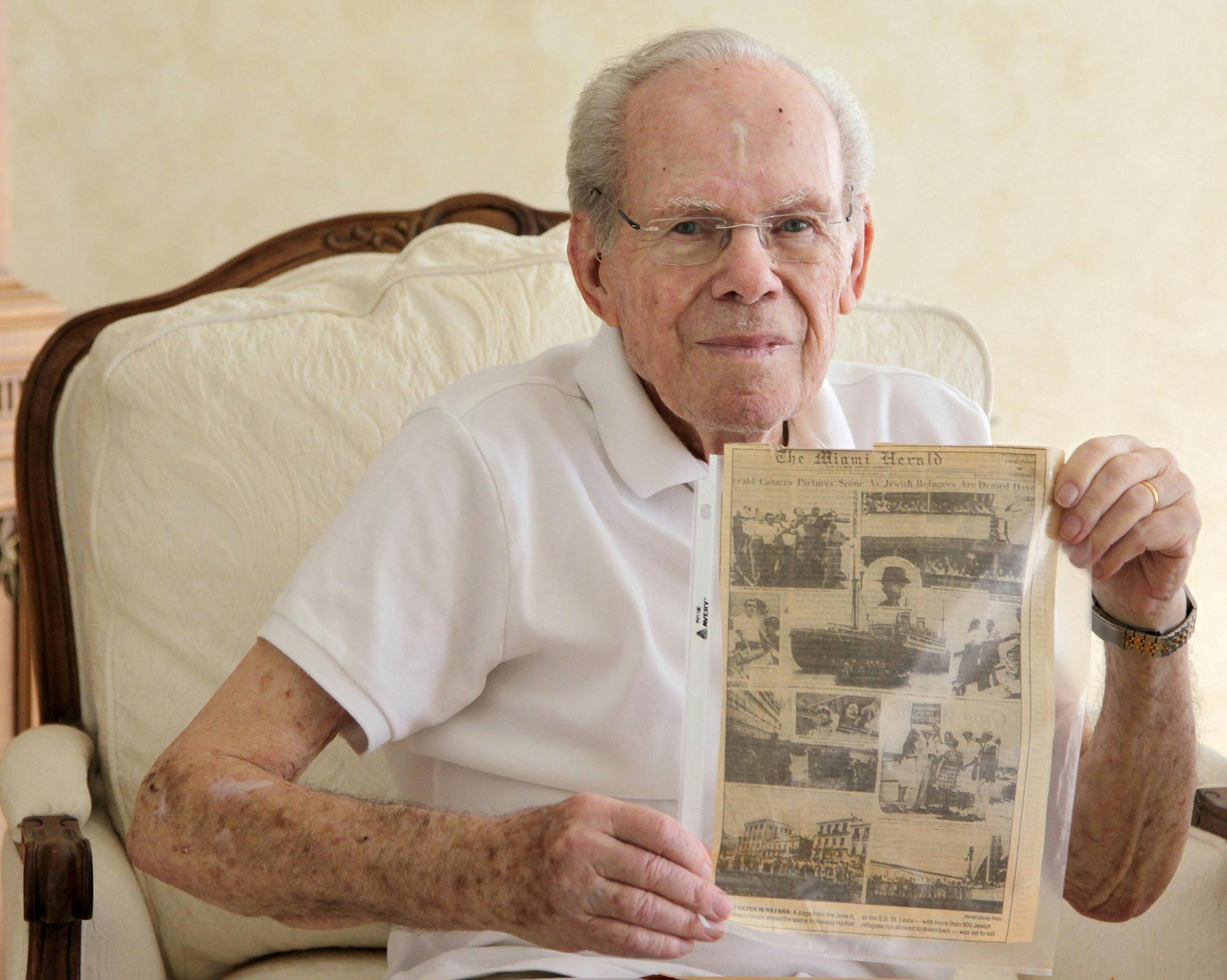 Herbert Karliner, one of the survivors of the 900 Jewish refugees fleeing Hitler who were turned away from Miami when they arrived aboard the ocean liner, St. Louis, in 1939, shares photos and documents from his ordeal on Nov. 18, 2015 in Aventura, Fla. Karliner shows a section front of the Miami Herald's coverage of St. Louis being denied sanctuary in Cuba circa 1939. (Carl Juste/Miami Herald/TNS)