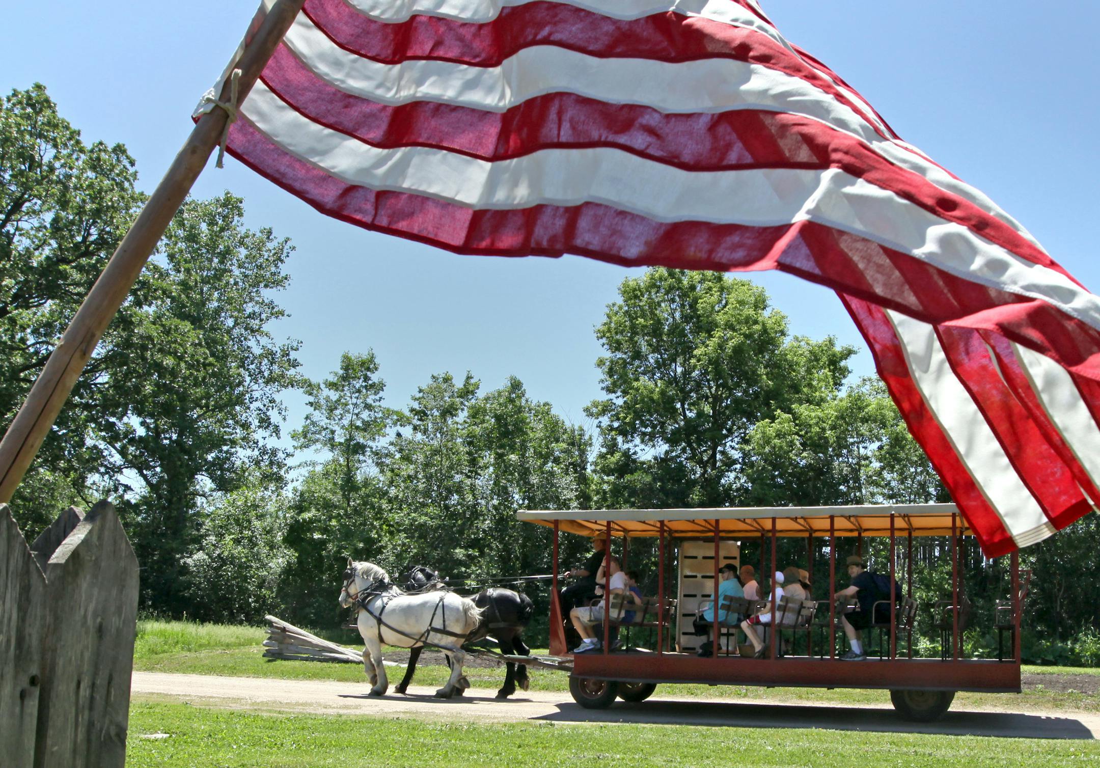 BRUCE BISPING • bbisping@startribune.com Shakopee, MN., Saturday, 5/29/2010] An American flag framed a Percheron horse-drawn trolley as it passed by historic buildings at "The Landing" during it's Memorial Day Encampment celebration. The memorial weekend activities include drills by the 5th Minnesota Civil War reenactors, trolley rides, and 1800's craft demonstrations. On Monday activities include Wilderness Inquiry canoe rides, music at the gazebo, a period baseball game, memorial day ce