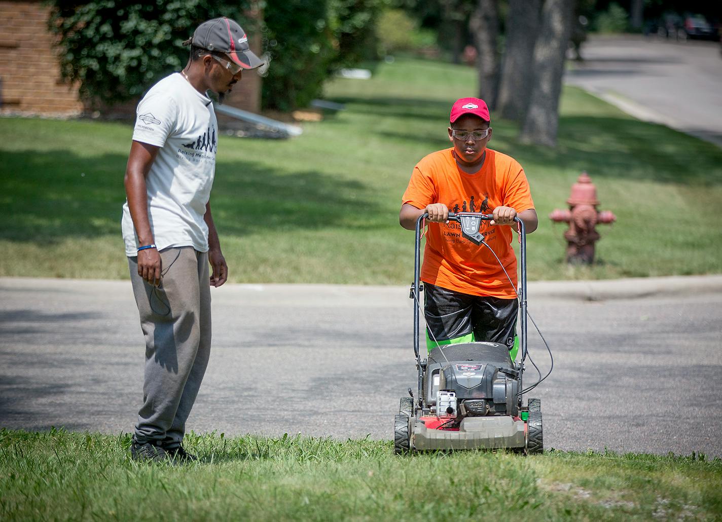 After mowing a lawn in St. Paul, Rodney Smith, left, got help from 12-year-old Tyquan Brown, as they mowed their third lawn of the day in Smith's forty-eighth state on Thursday, July 12, 2018, in Hopkins. Smith will move onto Alaska tomorrow. He said he received a call from God to help others by mowing his way across country.