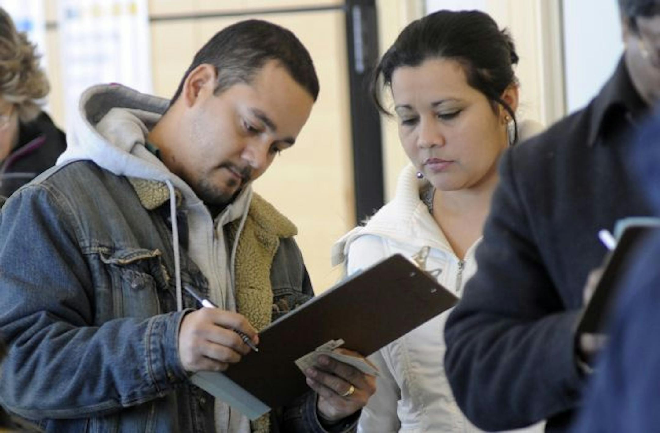 People fill out paperwork while in line at the Anoka County H1N1 Vaccination Clinic held at the Schwan's Center at the National Sports Center in Blaine, Minn., on Wednesday, Dec. 16, 2009.