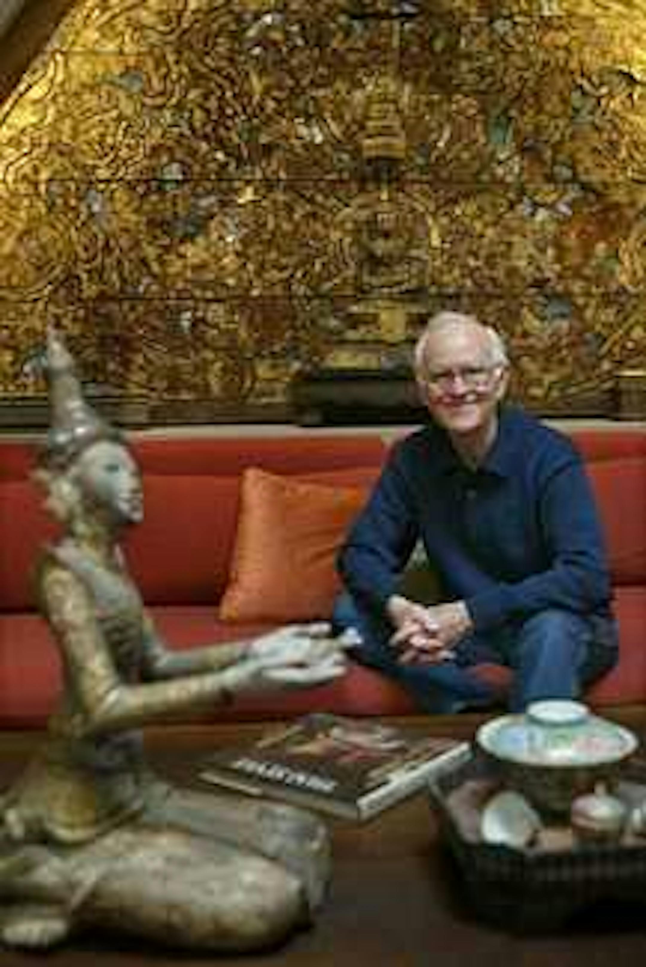 A gabled section from a Thai temple wall forms a gilded backdrop for a pair of carved figures from Burma.