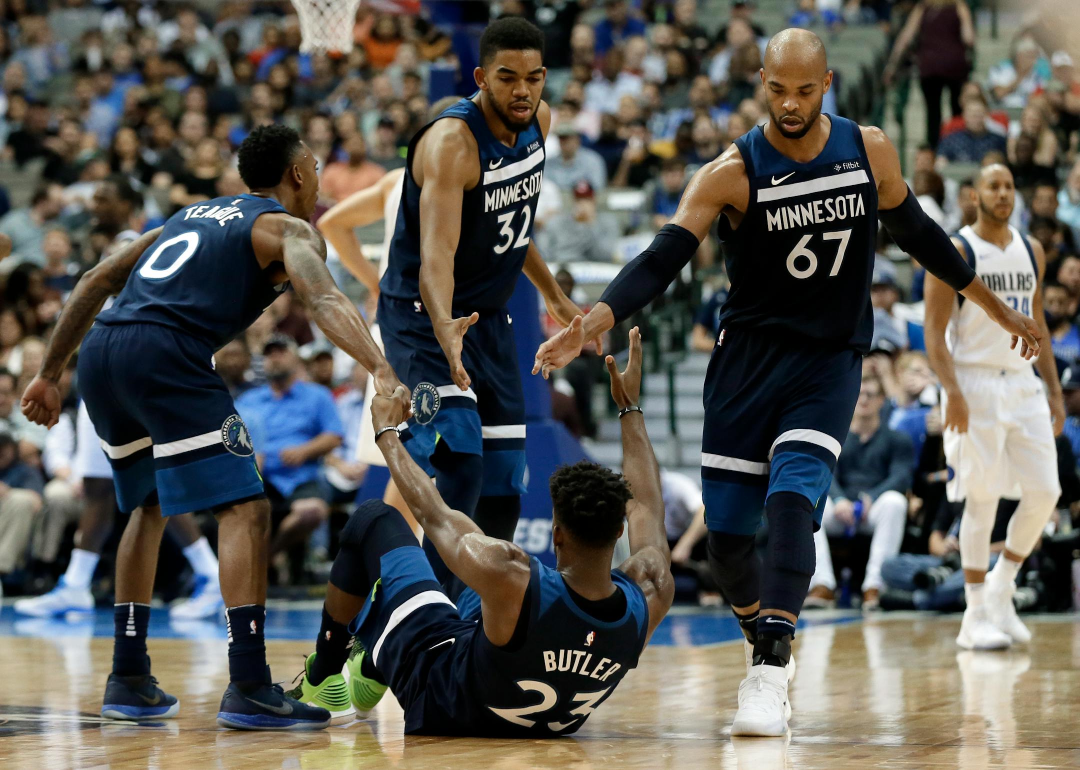 Minnesota Timberwolves' Jeff Teague (0), Karl-Anthony Towns (32) and Taj Gibson help Jimmy Butler (23) off the floor during an NBA basketball game against the Dallas Mavericks on Friday, Nov. 17, 2017, in Dallas. (AP Photo/Tony Gutierrez)