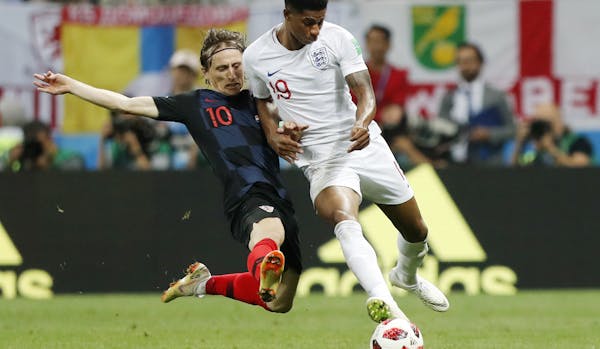 Croatia's Luka Modric, left, and England's Marcus Rashford challenge for the ball during the semifinal match between Croatia and England at the 2018 s