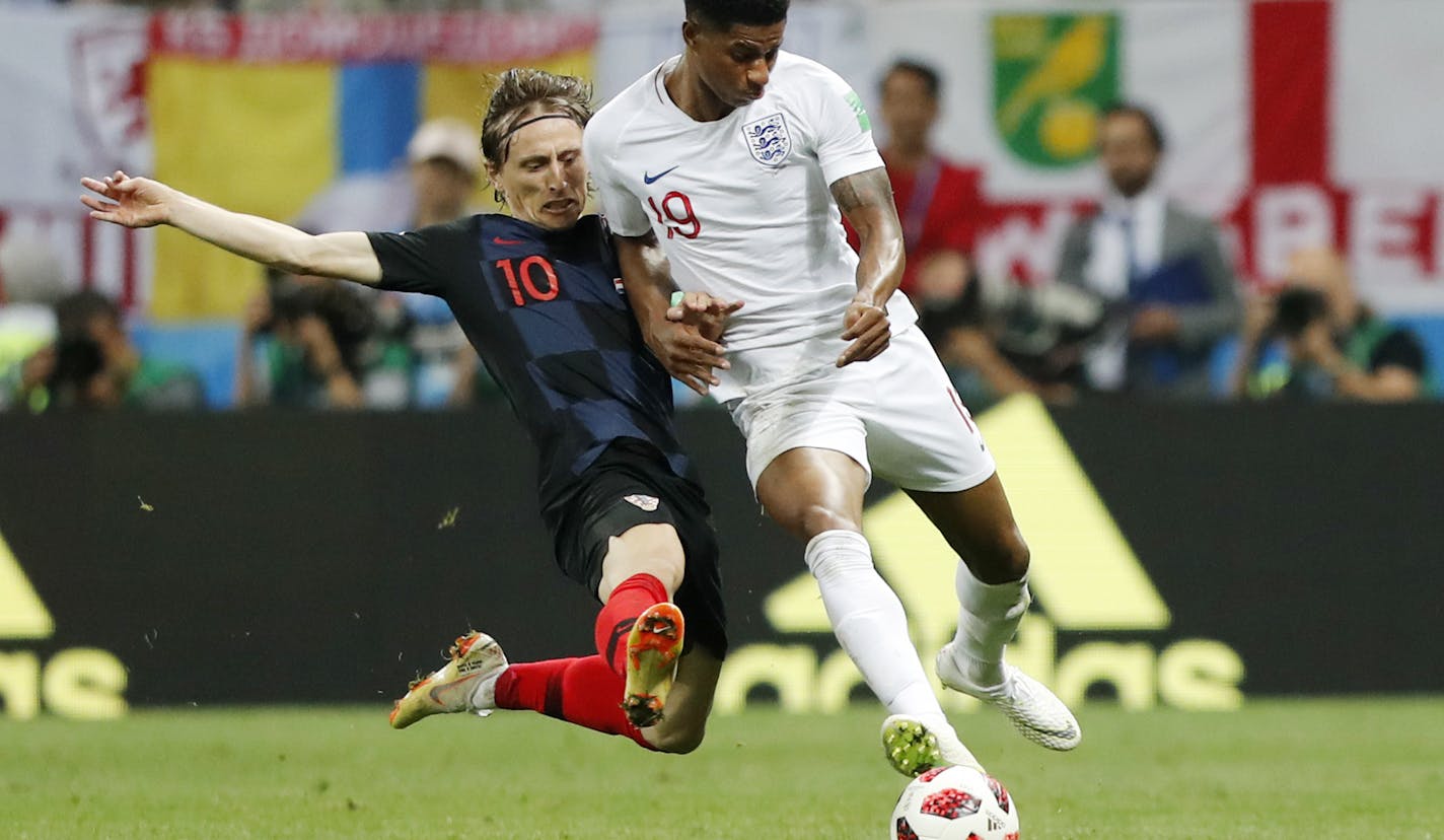 Croatia's Luka Modric, left, and England's Marcus Rashford challenge for the ball during the semifinal match between Croatia and England at the 2018 soccer World Cup in the Luzhniki Stadium in Moscow, Russia, Wednesday, July 11, 2018. (AP Photo/Frank Augstein)