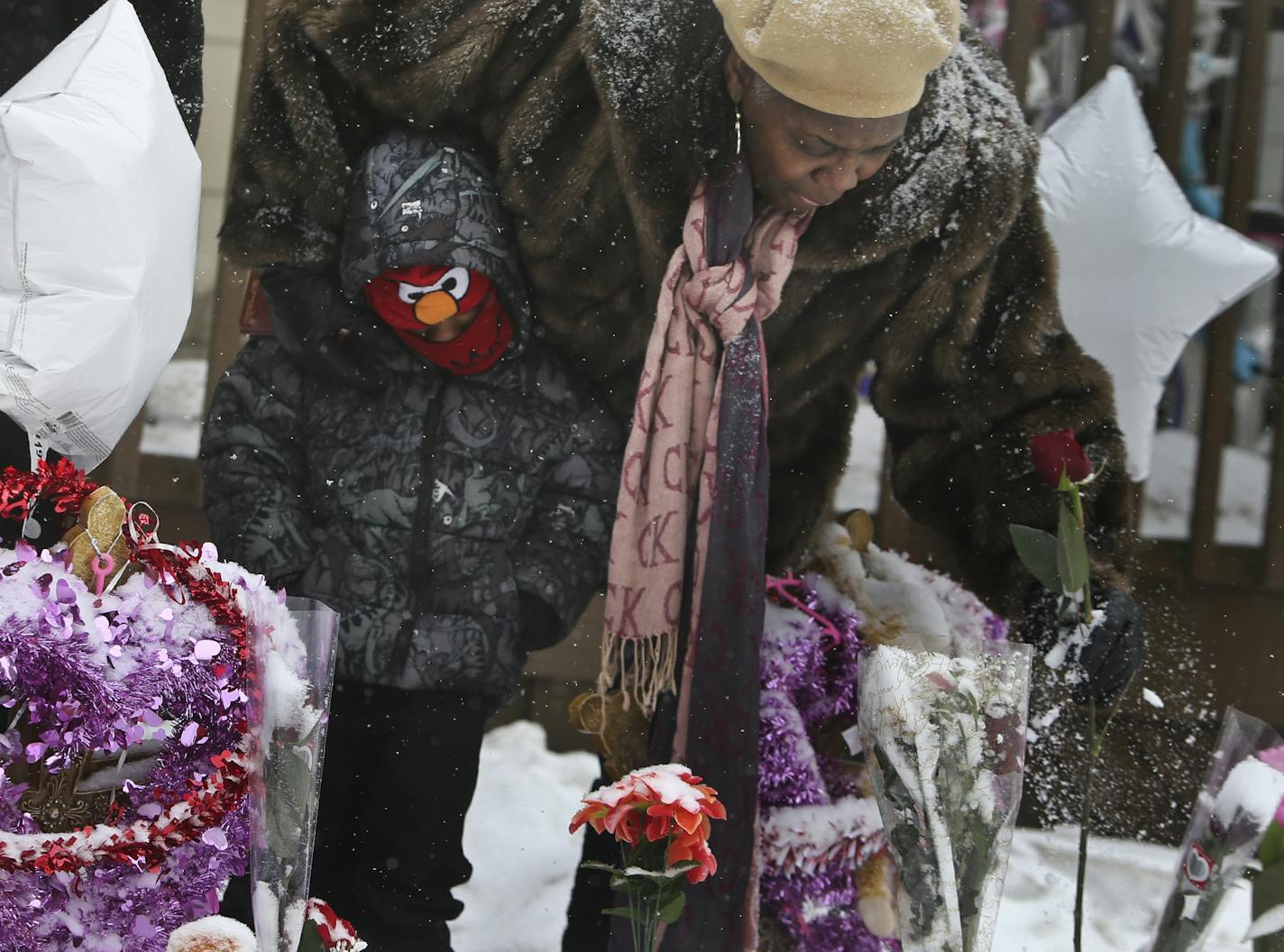 Zach Tate, 5, watches as his grandmother Shirley Williams, shakes snow off of a rose during a vigil held outside the charred duplex at 2818 Colfax Ave. N. Saturday, Feb. 15, 2014, in Minneapolis, MN. A day earlier five siblings, including three children, lost their lives in a fire at the north side duplex.](DAVID JOLES/STARTRIBUNE) djoles@startribune.com A day after a northside fire took the lives of five, including three children, a steady stream of vehicles with onlookers inside rolled slowly