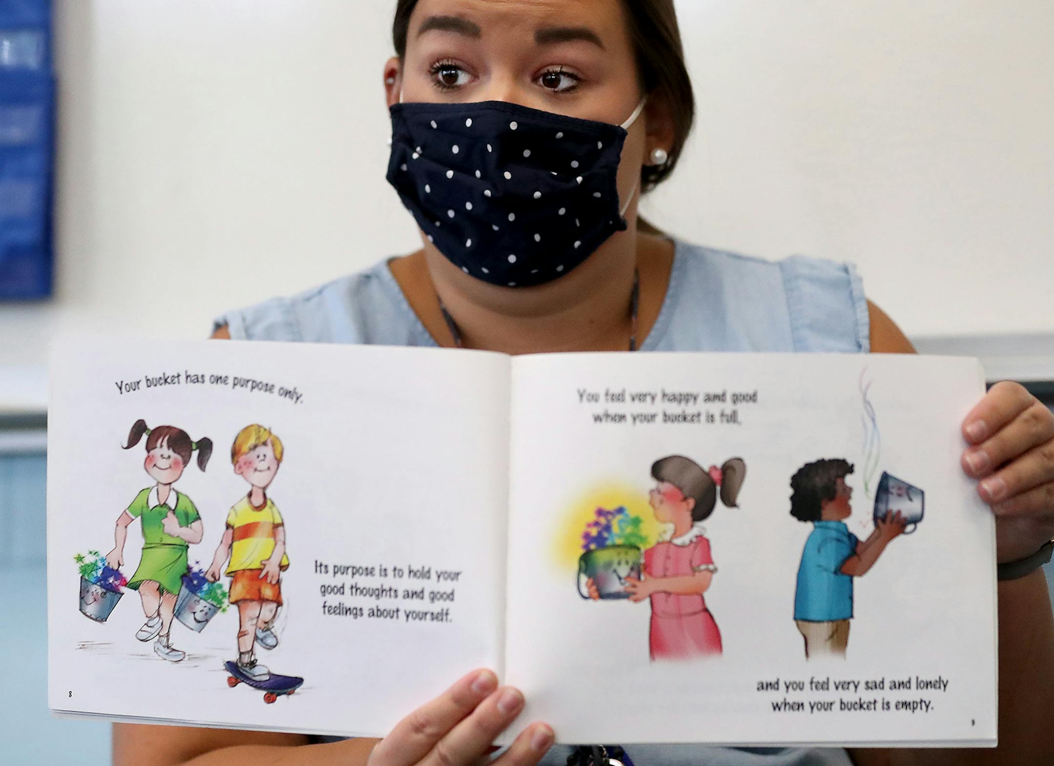 It was back to school for some students at Harvest Best Academy Tuesday in Minneapolis, but with masks, plastic barriers and other new precautions in the era of COVID-19. Here, Harvest Best Academy kindergarten teacher Sarah Swanson during reading time in her learning pod.