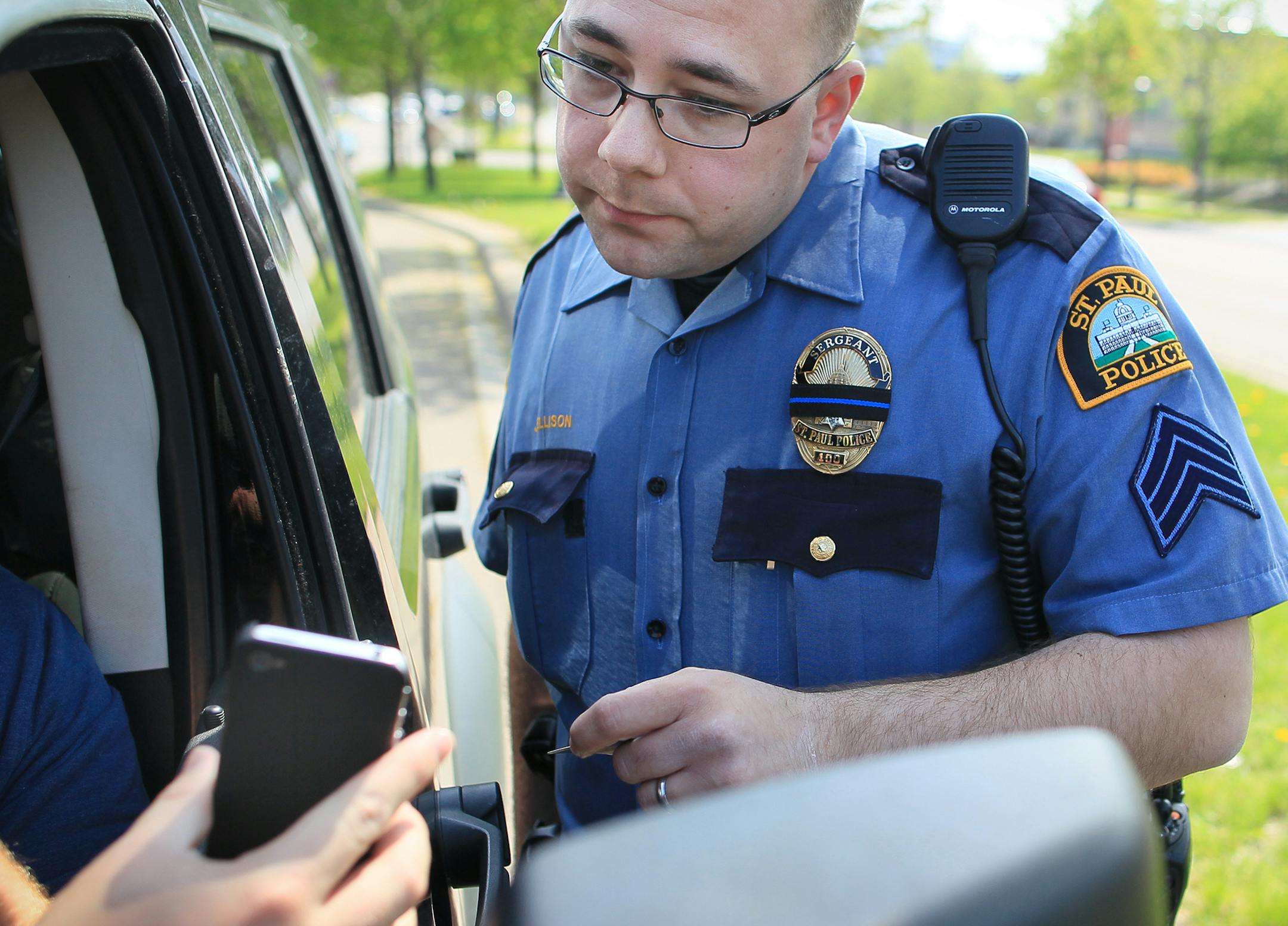 St. Paul police officer Jeremy Ellison looked at what a driver admitted to viewing on his cell phone while he was at a traffic light on Lexington Avenue on Wednesday, April 25, 2012 in St. Paul, Minn. after getting pulled over as law enforcement steps up enforcement of distracted driving, sometimes more easily spottable for officers at traffic lights. ] (RENEE JONES SCHNEIDER/ reneejones@startribune.com) Jeremy Ellison ORG XMIT: MIN2014072411030820