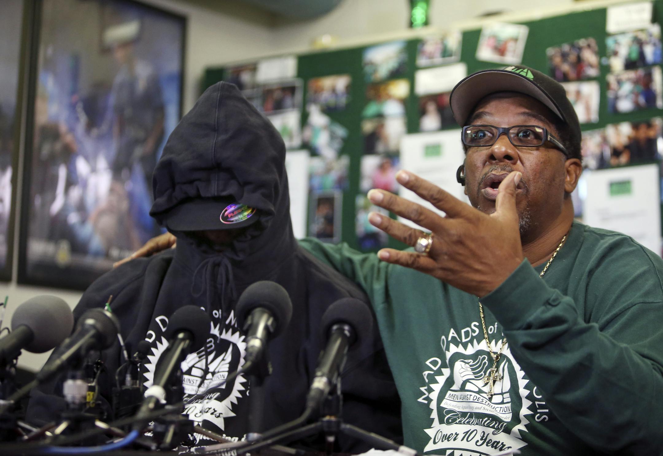 The father of 9-year-old plane stowaway, his face covered in a hoodie and hat to ensure his anonymity, talked to media members, sometimes through sobs, as he was accompanied by MAD DADS V.J. Smith, right, Wednesday, Oct. 9, 2013.