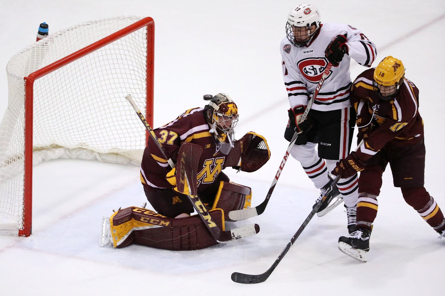 St. Cloud State Huskies forward Jacob Benson (17) tried to deflect the puck past Minnesota Golden Gophers goaltender Eric Schierhorn (37) as Minnesota Golden Gophers forward Brent Gates Jr. (10) defended in the third period.