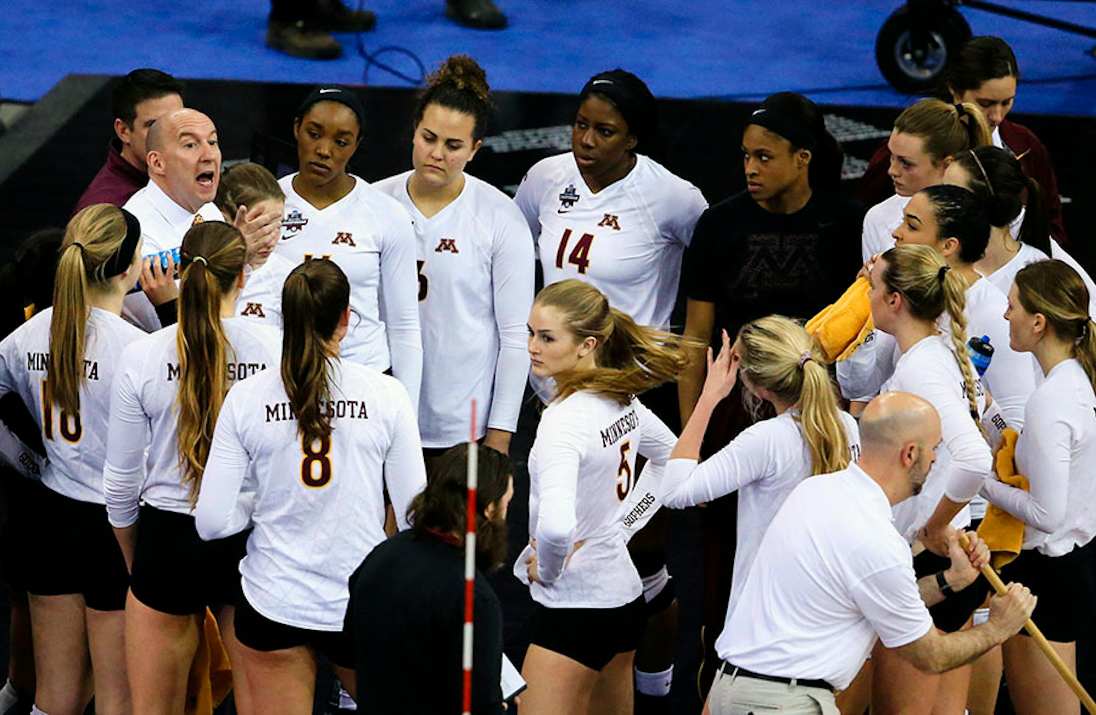 Minnesota coach Hugh McCutcheon, left, talks to his players during a timeout in an NCAA women's volleyball tournament semifinal against Texas in Omaha, Neb., Thursday, Dec. 17, 2015.