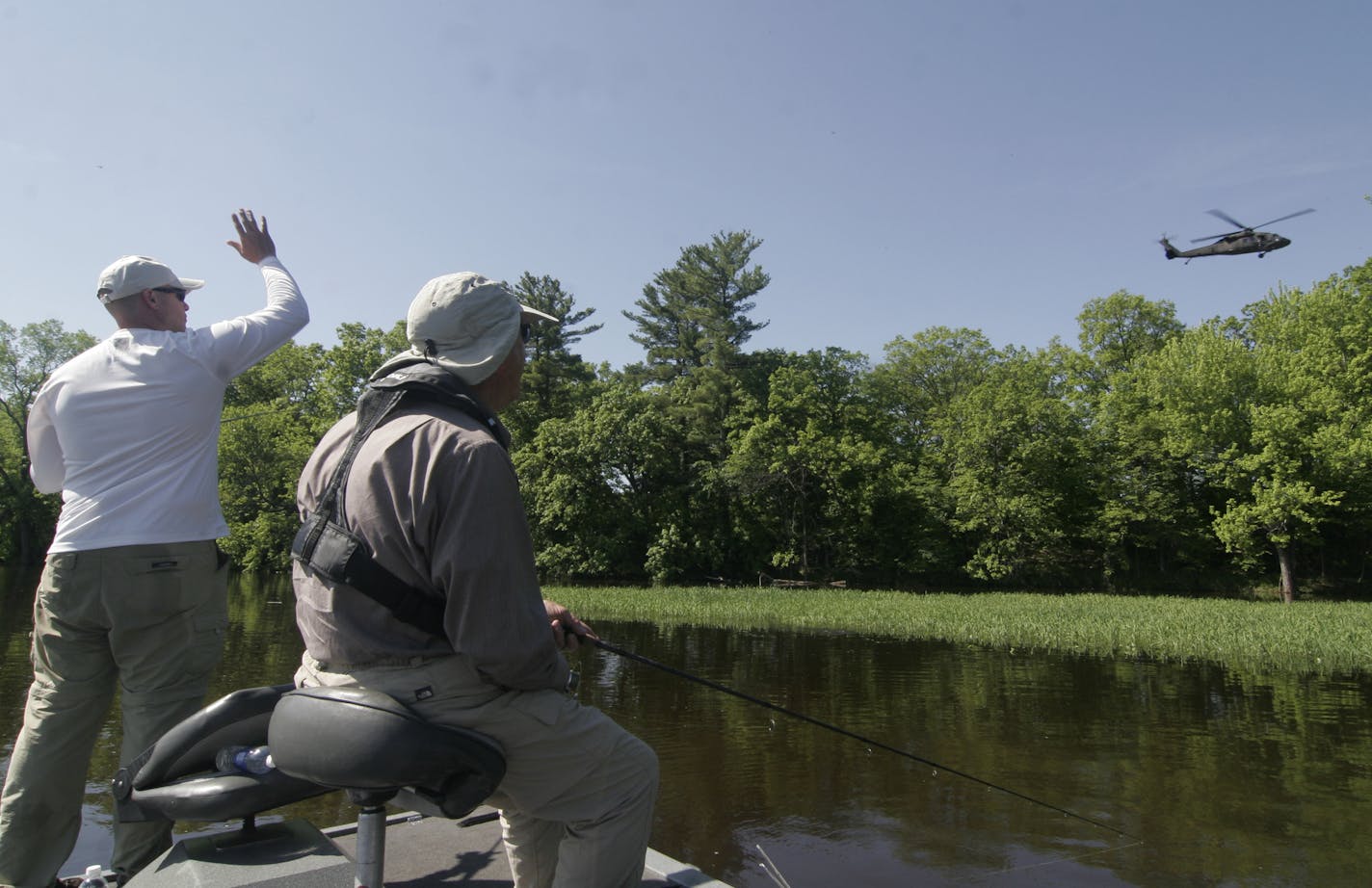 Nate Foster, an Army helicopter pilot, waves to a Blackhawk helicopter that flew over the Mississippi River on Frday and Foster and his grandfather, Swede Anderson, fished.