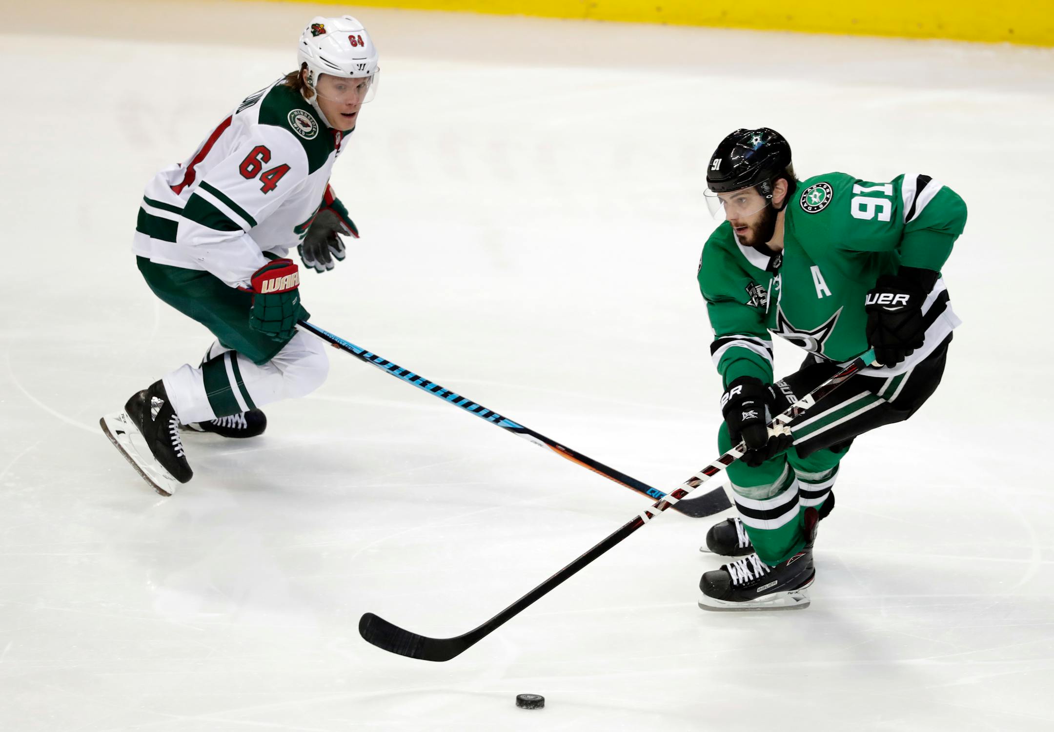 Minnesota Wild's Mikael Granlund (64) defends as Dallas Stars center Tyler Seguin (91) handles the puck in the third period of an NHL hockey game in Dallas, Saturday, March 31, 2018. (AP Photo/Tony Gutierrez)